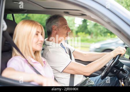 Coppia anziana felice che va in viaggio in macchina Foto Stock