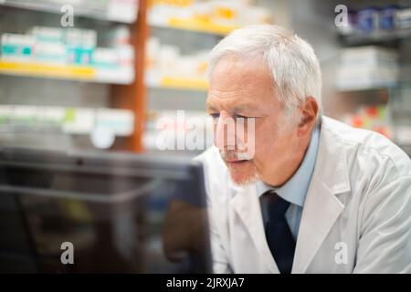 Farmacista che lavora con un bicchiere in farmacia Foto Stock