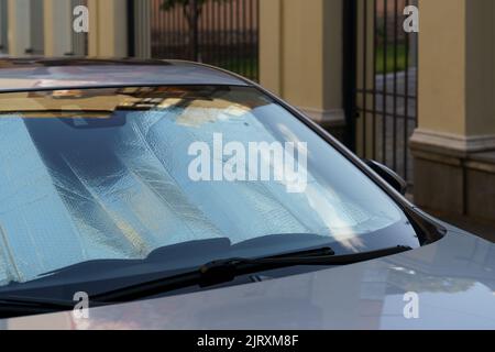 Superficie riflettente protettiva sotto il parabrezza dell'auto nelle giornate calde, riscaldata dai raggi del sole all'interno dell'auto Foto Stock