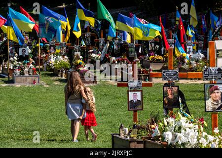 Lviv, Ucraina. 26th ago, 2022. Una famiglia arriva per rispettare le tombe di soldati caduti, uccisi dall'esercito russo durante l'invasione del 2022 nella città vecchia di Lviv al cimitero di Lychakiv, mentre la guerra con la Russia supera i 6 mesi. La città di Lviv ha selezionato una fessura separata di terra al cimitero per i soldati caduti nella lotta con la Russia, i militari sono ampiamente considerati come eroi nazionali. (Credit Image: © Dominika Zarzycka/SOPA Images via ZUMA Press Wire) Credit: ZUMA Press, Inc./Alamy Live News Foto Stock