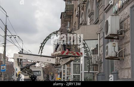 Dnepropetrovsk, Ucraina - 12.20.2021: Un operaio decora una strada cittadina. Installazione dell'illuminazione festiva. Prepararsi per il nuovo anno e C Foto Stock