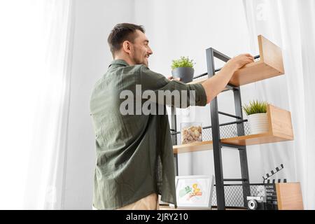 l'uomo che decora la casa con e che dispone la mensola Foto Stock