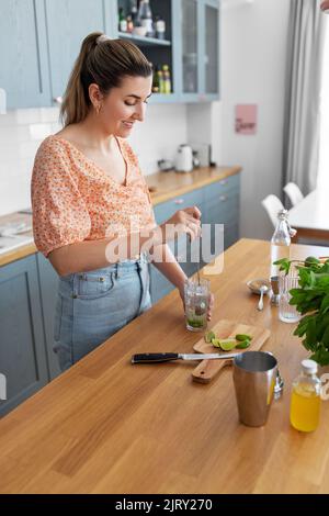 donna che fa cocktail bevande in cucina a casa Foto Stock