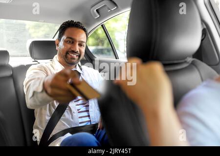 uomo indiano che dà carta di credito al tassista Foto Stock