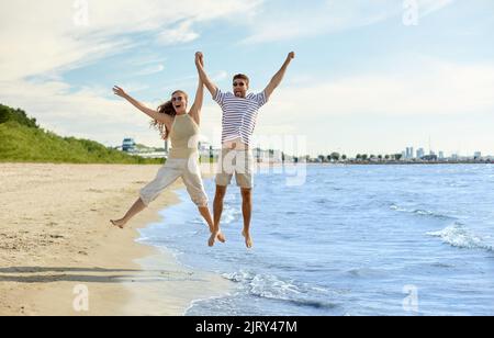 felice coppia che salta sulla spiaggia estiva Foto Stock
