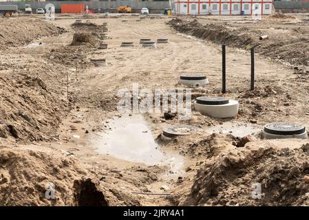 Le botole fognarie hanno sviluppato tubi di drenaggio in calcestruzzo tra grandi aree residenziali. Nuova fognatura sanitaria, impianti di scarico in cantiere. Foto Stock