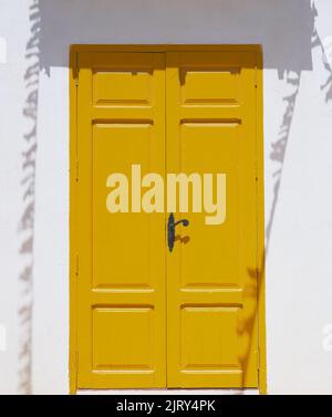 particolare di una porta gialla all'ombra su una parete dipinta di bianco Foto Stock