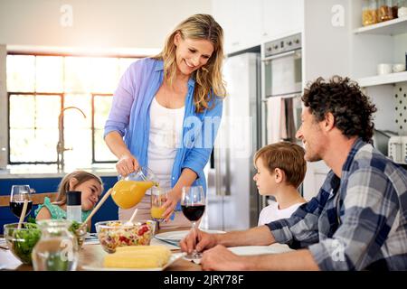 Il cibo ha un sapore migliore quando lo si gode con la famiglia. Una famiglia felice gustando un pasto insieme a casa. Foto Stock