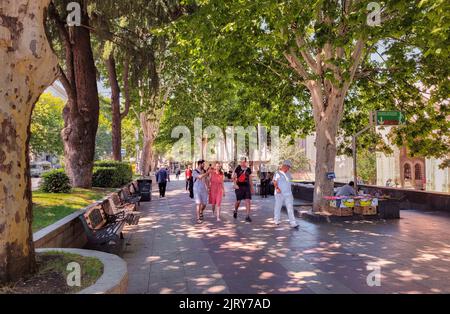 Tbilisi, Georgia - 07 23 2022: Vista estiva lungo il vicolo di Shota Rustaveli Avenue con turisti e cittadini che camminano sotto il verde lussureggiante fogliame di Foto Stock