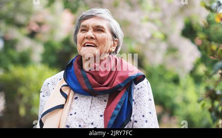 Ritratto felice vecchia donna sorridente godendo pensione indossando sciarpa colorata in bel giardino Foto Stock