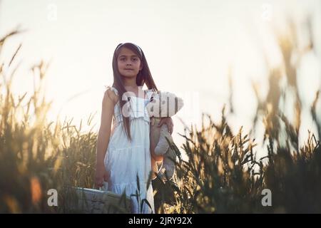 Erano pronti a lasciare la fattoria. Ritratto di una ragazza carina che gioca con il suo orsacchiotto in un campo di mais. Foto Stock
