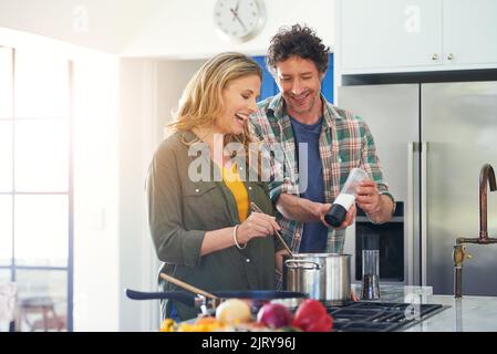 Una coppia matura e felice che prepara un pasto insieme a casa. Foto Stock