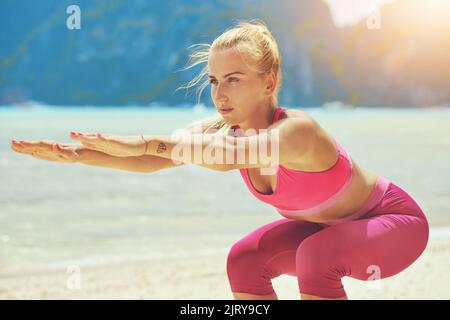 Raggiungete il vostro corpo perfetto. Una giovane donna concentrata che fa yoga sulla spiaggia. Foto Stock