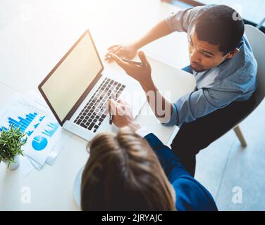 Due menti sono meglio di una. Ripresa ad alta angolazione di due giovani colleghi che utilizzano un notebook insieme in ufficio. Foto Stock