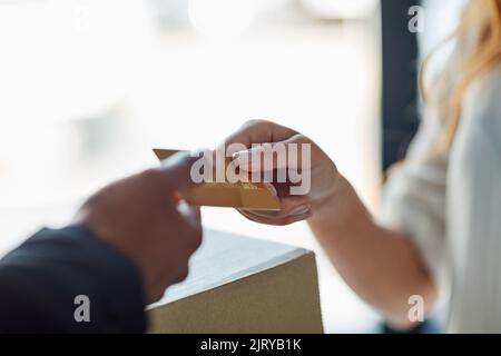 Pagamento semplice. Un cliente che utilizza una carta di credito per pagare una consegna effettuata da un corriere. Foto Stock