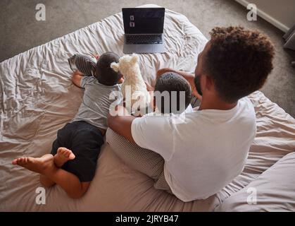 Tecnologia, uomo e bambini si rilassano a letto insieme per legare e divertirsi nel fine settimana. Felice padre che ha tempo di qualità con i suoi figli a casa di famiglia Foto Stock