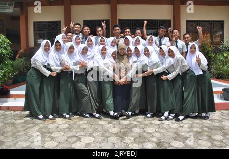 Tegal, INDONESIA, 11 Apr 2018 - Un gruppo di studenti con un insegnante di casa che scatta una foto insieme per un album di laurea Foto Stock