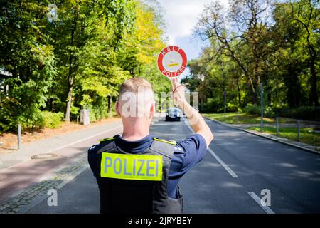 Berlino, Germania. 24th ago, 2022. Un ispettore senior della polizia di Berlino ferma un'auto durante un controllo del traffico effettuato dalla polizia di Berlino su Fulhamer Allee, nel quartiere Neukölln di Berlino, vicino a una scuola. (A dpa: 'I trasgressori di traffico portano gli stati e i comuni più entrate') Credit: Christoph Soeder/dpa/Alamy Live News Foto Stock