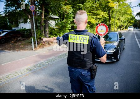 Berlino, Germania. 24th ago, 2022. Un ispettore senior della polizia di Berlino ferma un'auto durante un controllo del traffico effettuato dalla polizia di Berlino su Fulhamer Allee, nel quartiere Neukölln di Berlino, vicino a una scuola. (A dpa: 'I trasgressori di traffico portano gli stati e i comuni più entrate') Credit: Christoph Soeder/dpa/Alamy Live News Foto Stock