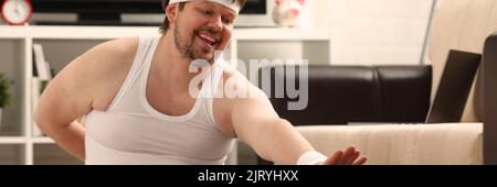 L'uomo di idoneità si trova su tappeto spesso con peso in eccesso, esegue esercizi di stretching Foto Stock