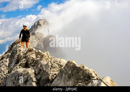 Alpinista che sale sul crinale di Watzmann, nella parte posteriore della cima media, traversata di Watzmann, Alpi Berchtesgaden, Parco Nazionale di Berchtesgaden, Schoenau Foto Stock