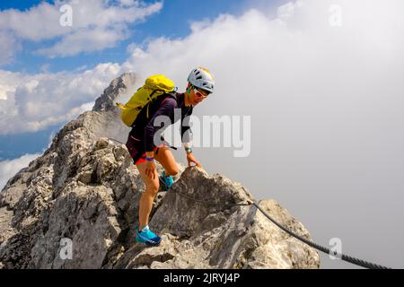 Alpinista che sale sul crinale di Watzmann, nella parte posteriore della cima media, traversata di Watzmann, Alpi Berchtesgaden, Parco Nazionale di Berchtesgaden, Schoenau Foto Stock