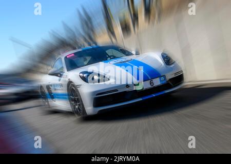 Foto dinamica con effetto zoom della vettura sportiva da corsa bianca con striscia blu Porsche 718 Cayman GTS in uscita dalla pit lane, circuito FIA di Formula 1 Foto Stock