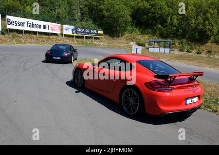 Due vetture sportive anteriori rosse Porsche Cayman GT4 con spoiler posteriore sullo sfondo Porsche 911 996 Carrera in corso di formazione sulla sicurezza di guida Foto Stock