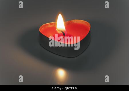 La piccola candela bruciante a forma di cuore isolato Foto Stock