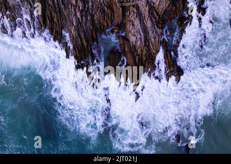 Vista aerea Top Down Seashore grande onda che si schiantano sulla scogliera di roccia bella superficie di mare scuro in giorno di sole estate sfondo incredibile mare vista dall'alto seac Foto Stock