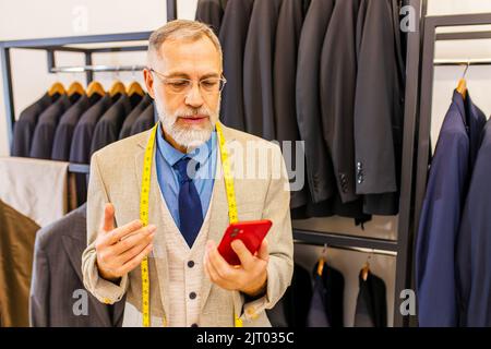 bell'uomo bearded maturo ben vestito che parla con il cliente per telefono nel suo studio atelier Foto Stock