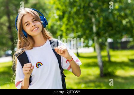 ragazza in età adolescente con zaino e cuffia nel concetto di ritorno a scuola parco Foto Stock