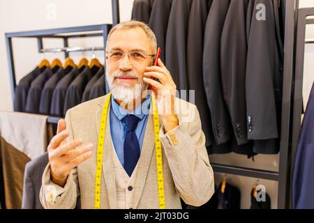 bell'uomo bearded maturo ben vestito che parla con il cliente per telefono nel suo studio atelier Foto Stock