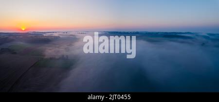 Alba rosso arancio brillante sui campi di fattoria nebbiosa di Roztocze Polonia. Paesaggio mattutino. Scatto orizzontale ampio. Foto di alta qualità Foto Stock