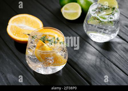 due bicchieri con un cocktail alcolico su fondo legno scuro. il seltzer duro è una bevanda a basso contenuto alcolico. Cocktail forti con lime Foto Stock