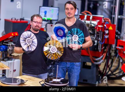 22 agosto 2022, Meclemburgo-Pomerania occidentale, Güstrow: Andre Kronert (r), e Daniel Slabschie (l), amministratore delegato della società discografica 'materia di fatto', mostrano alcuni dei dischi colorati pressati nella società. L'impresa con attualmente cinque colleghi produce per alcune settimane in un ex clamoroso patata che ha dovuto essere convertito complessamente per la produzione di dischi. Con una forza di 150 tonnellate, i dischi di lunga durata sono prodotti sulle presse a 200 gradi Celsius da cloruro di polivinile (PVC). Ogni anno devono essere premuti tra 250.000 e 300.000 record. Secondo il Ger Foto Stock