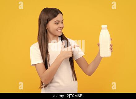 bambino allegro punta il dito sul prodotto di bevanda di caseificio. ragazza teen che va bere il latte Foto Stock