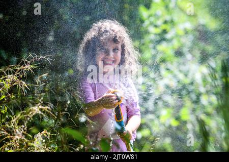 27th agosto 2022, Swansea, Galles.**IL CONSENSO DEI GENITORI OTTENUTO E AUTORIZZATO PER IL BAMBINO IN PIC** nella foto è gioia di Lillian di quattro anni che ha una lotta con gli amici in acqua in un fine settimana caldo di festa della Banca nel Galles del Sud dove non ci è divieto del hosepipe. Foto Stock