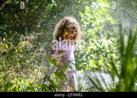 27th agosto 2022, Swansea, Galles.**IL CONSENSO DEI GENITORI OTTENUTO E AUTORIZZATO PER IL BAMBINO IN PIC** nella foto è gioia di Lillian di quattro anni che ha una lotta con gli amici in acqua in un fine settimana caldo di festa della Banca nel Galles del Sud dove non ci è divieto del hosepipe. Foto Stock