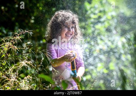 27th agosto 2022, Swansea, Galles.**IL CONSENSO DEI GENITORI OTTENUTO E AUTORIZZATO PER IL BAMBINO IN PIC** nella foto è gioia di Lillian di quattro anni che ha una lotta con gli amici in acqua in un fine settimana caldo di festa della Banca nel Galles del Sud dove non ci è divieto del hosepipe. Foto Stock