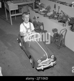 Ragazzo negli anni '1950s. Alla fiera annuale di Stoccolma, uno stand con giocattoli per bambini espone i giocattoli più recenti disponibili sul mercato. Il ragazzo prova la pedalata fuori e sembra felice. Svezia 1952 Conard Ref 2112 Foto Stock