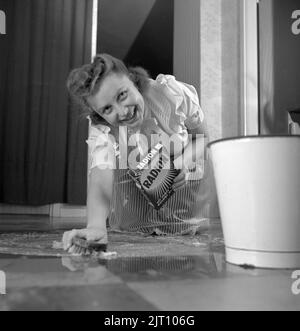 Pulire il pianale sul retro. Una giovane donna è sdraiata sul pavimento e sta strofinando per pulire il pavimento. Svezia 1952 Conard Ref 2220 Foto Stock