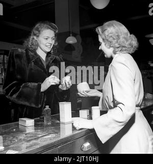 Shopping nel 1940s. Una giovane donna in un negozio in cui una donna di vendita sta presentando alcuni dei negozi selezione di profumi e cosmetici. Svezia 1947. Kristoffersson rif Y71-1 Foto Stock