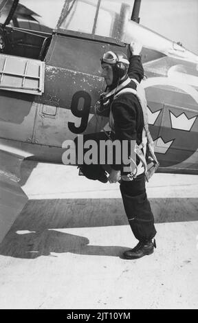 Pilota negli anni '1940s. Un pilota nel suo aereo con gli auricolari visibili nel cappuccio in pelle è pronto per il decollo. Le cinghie del suo paracadute sono visibili. Svezia 1944 Foto Stock