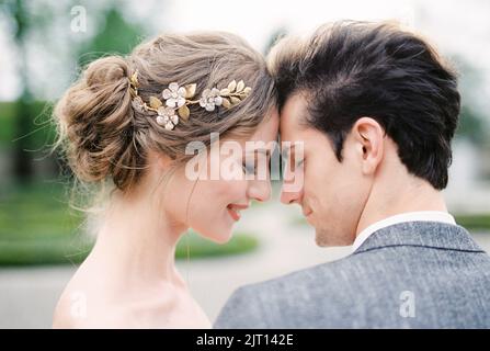 La sposa sorridente tocca la fronte con la fronte. Verticale Foto Stock