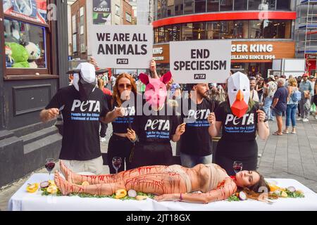 Londra, Regno Unito. 27th agosto 2022. Gli attivisti DI PETA indossano maschere animali 'dine' su un essere umano coperto di sangue falso in Leicester Square. L'azione, che segna la Giornata Mondiale per la fine dello Specialismo, fa parte della campagna in corso della PETA per porre fine allo specialismo e incoraggiare le persone ad andare vegane. Credit: Vuk Valcic/Alamy Live News Foto Stock