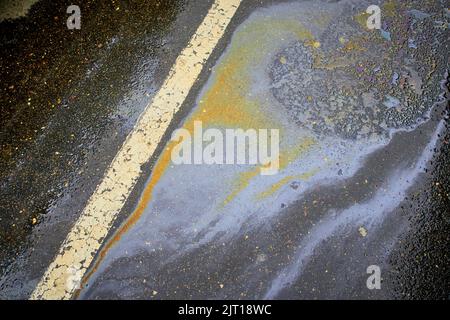 Fuoriuscita di benzina sull'asfalto con una striscia divisoria bianca in un parcheggio come una texture o sfondo. Foto Stock