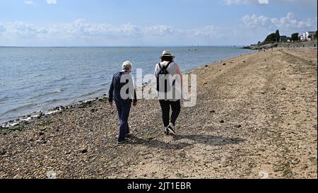 Shoeburyness. Regno Unito. 27 agosto 2022. Due donne camminano lungo la ciottola a Shoeburyness East Beach, Essex, Regno Unito Foto Stock