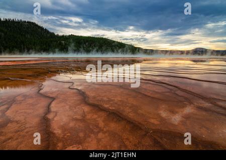 Le piscine poco profonde che circondano il Grand Prismatic Spring riflettono il tramonto nel Parco Nazionale di Yellowstone Foto Stock