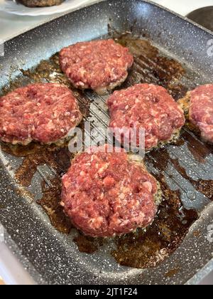 Le cotolette di hamburger rossi si friggano in una padella Foto Stock